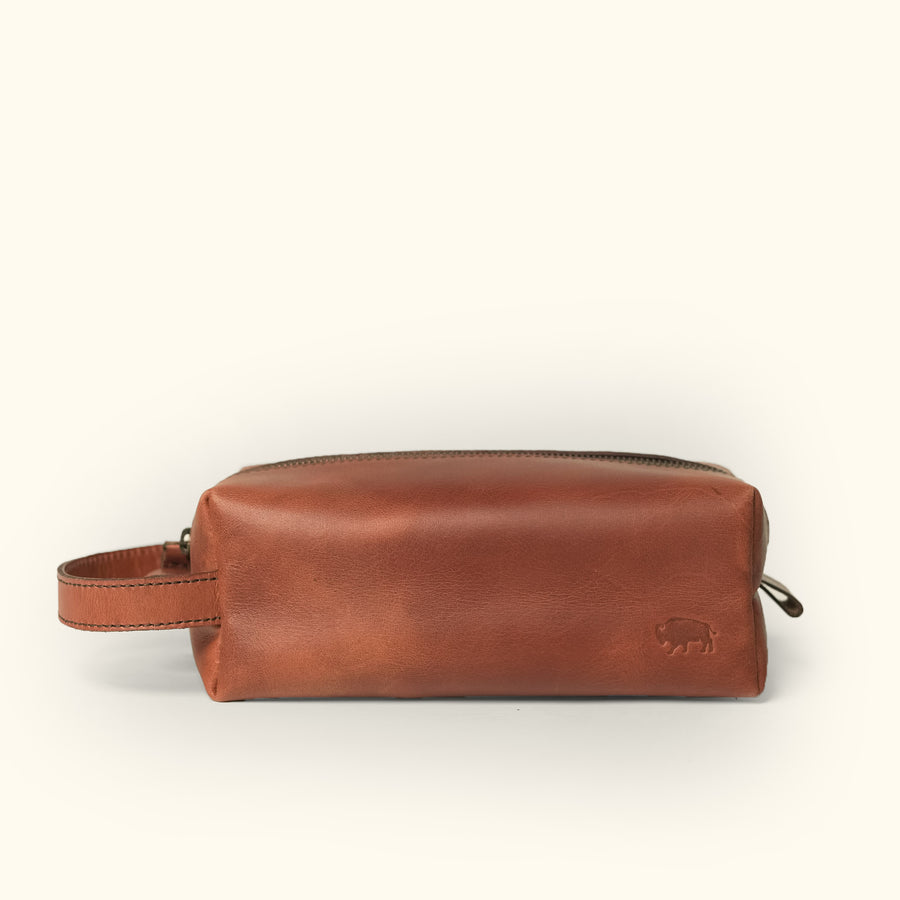 Amber brown Roosevelt buffalo leather dopp kit with wrist strap and embossed logo detail.