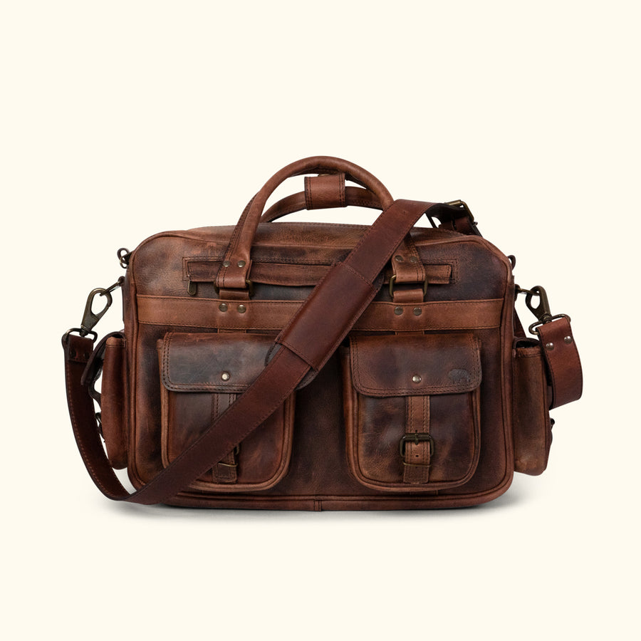 Men's rugged leather pilot bag in dark oak with multiple compartments, brass buckles, adjustable strap, and detachable pouches. Ideal for travel.